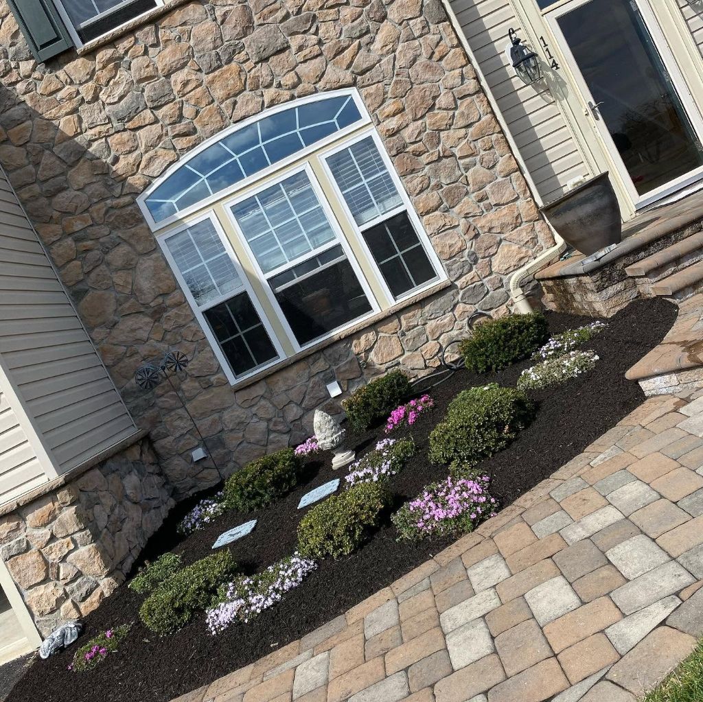 Professional mulch installation — fresh dark mulch with flowering shrubs and plants South Jersey