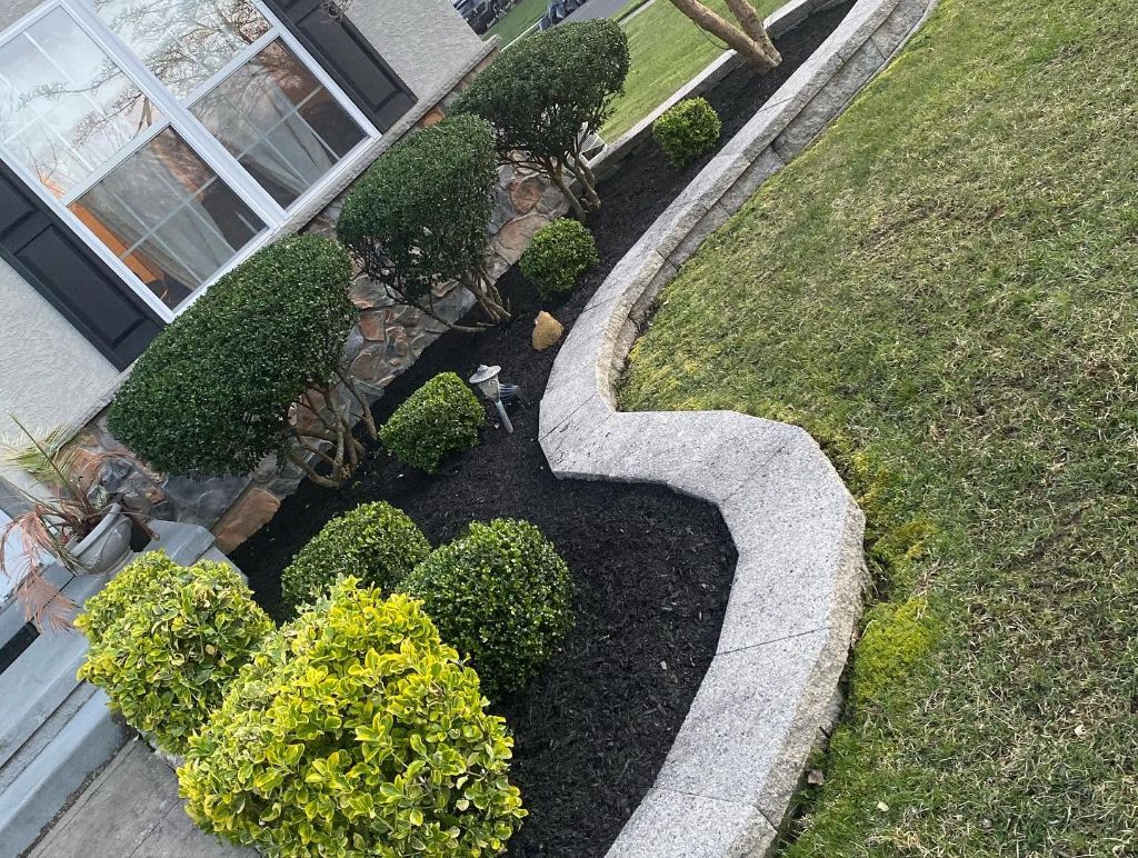 Black mulch foundation beds with trimmed shrubs and granite curbing