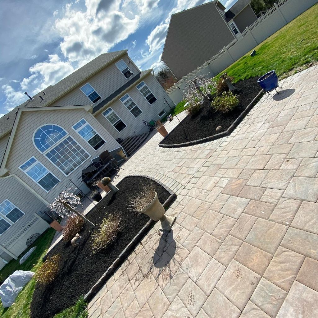 Stamped paver patio with curved landscape beds — professional hardscaping South Jersey